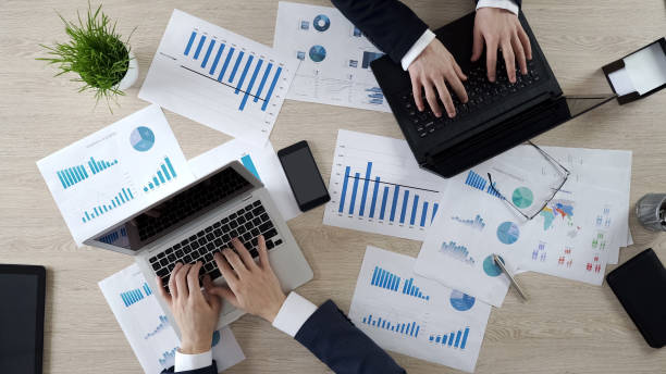 istock Two corporate employees typing on laptops, working on business project, top view 951481368