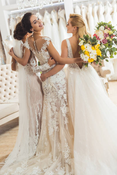 istock Young smiling brides with bouquets in wedding atelier 951489480
