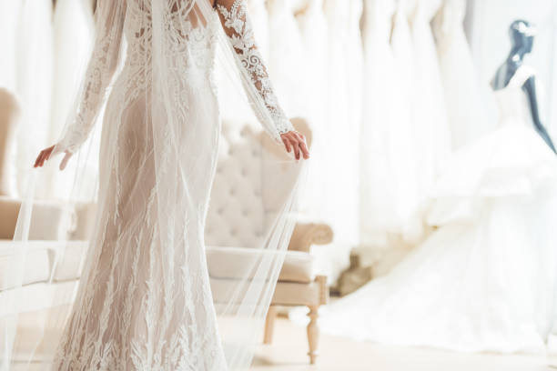 Cropped view of bride in lace dress in wedding salon Cropped view of bride in lace dress in wedding salon bridal shop photos stock pictures, royalty-free photos & images