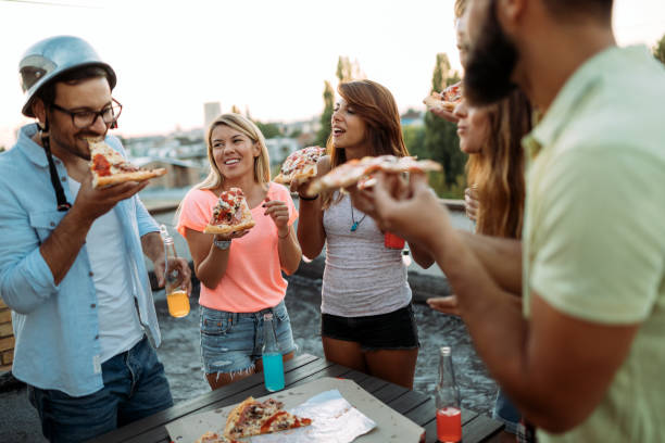 istock Group of young people sitting around and eating pizza 951490020