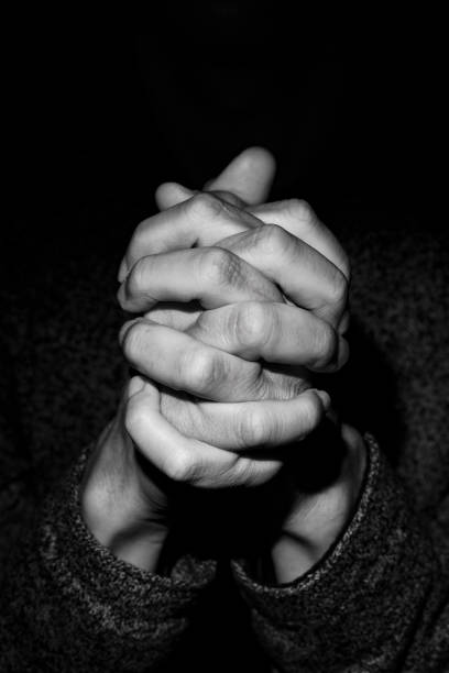 man with his hands clasped, in black and white closeup of the hands of a young caucasian man with his hands clasped, in black and white national day of prayer stock pictures, royalty-free photos & images