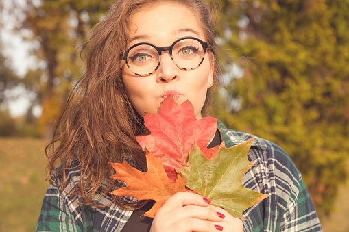 Cute smiling woman hiding behind the leafs in nature.