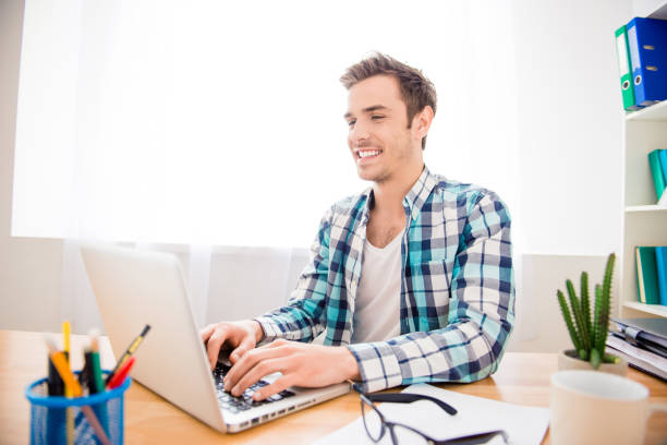 istock Cheerful happy man doing task and writing on laptop 951499570