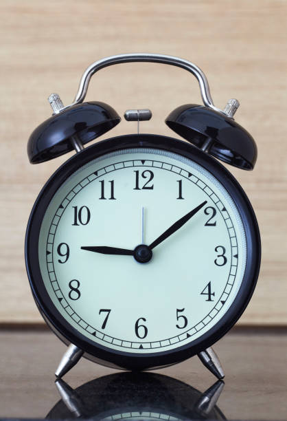 istock Black retro alarm clock on wood table 951500528