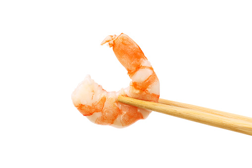 Peeled king prawn in chopsticks isolated against white