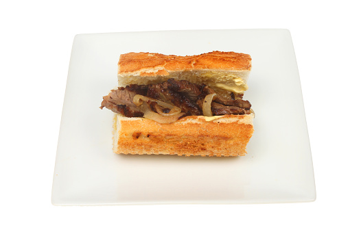 Steak and onion in a giraffe roll on a plate isolated against white