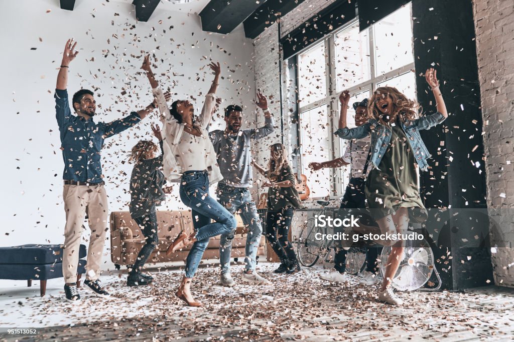 Best party! Full length of happy young people dancing while having a party with confetti flying everywhere Party - Social Event Stock Photo