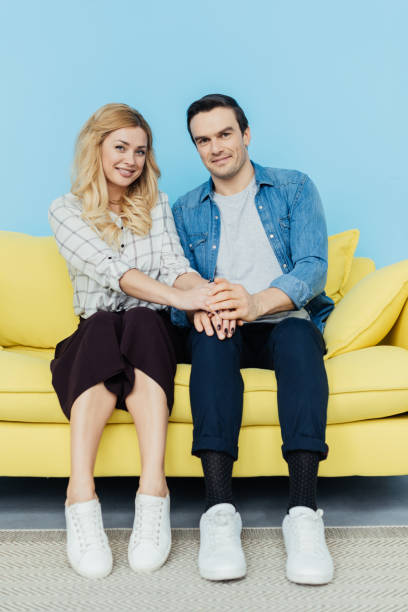 istock Happy couple sitting and holding hands on yellow sofa 951513242