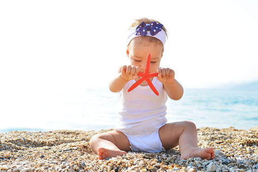 Cute blonde little girl eating ice cream on sandy beach. Summer vacation, happy childhood concept