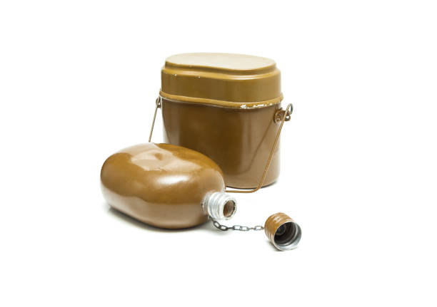 Military flask and loaded magazines resting on a wooden surface, evoking themes of conflict, survival, and wartime preparedness