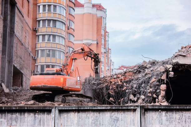 Excavator demolishes and destrys Excavator demolishes and destrys old buildings between new buildings deconstruct stock pictures, royalty-free photos & images