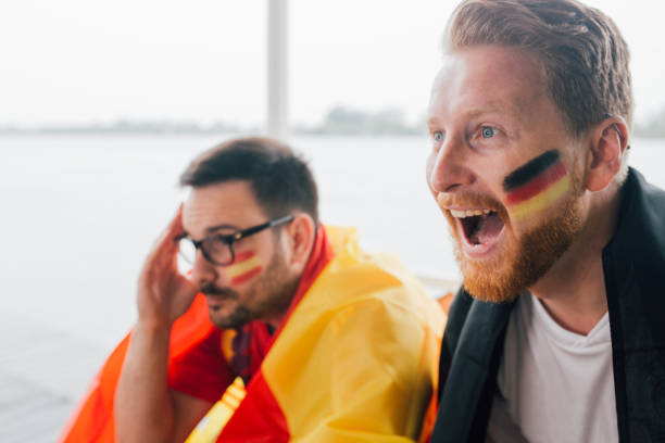 istock Ecstatic German football supporter watching game with friend supporting Spanish team 951525194