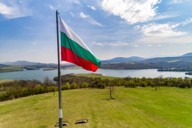 vista aérea de bulgaria bandera nacional ondeando con orgullo frente a un hermoso paisaje con lago y montañas - unesco world heritage site cloud day sunlight fotografías e imágenes de stock