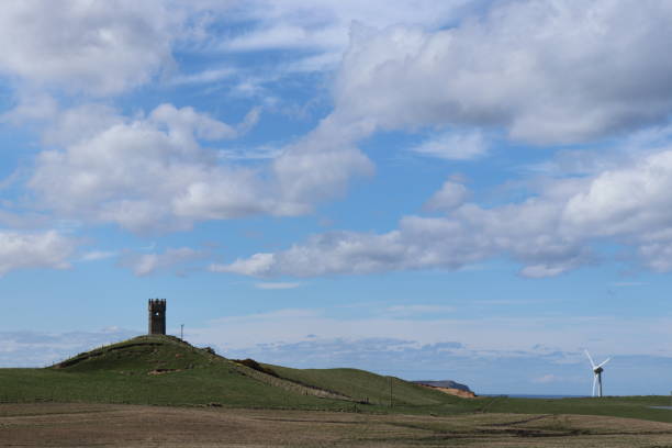 istock Old lookout tower on hill against blue sky with fluffy white cloudrs 951539852