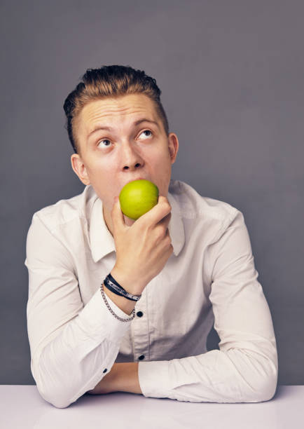 istock man eating apple, against dark background 951540478