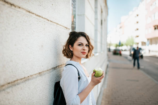 istock Gorgeous looking woman eating apple on street. 951551336