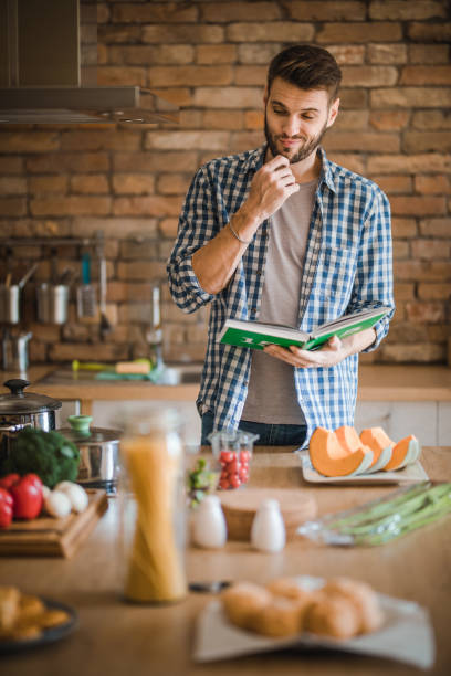 istock Thoughtful bachelor with a cookbook in the kitchen. 951551582