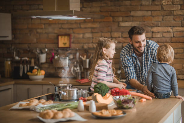 istock Happy father talking to his small kids while preparing lunch in the kitchen. 951551754