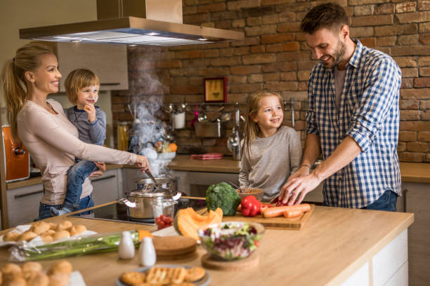 istock Young happy parents enjoying while preparing lunch with their kids in the kitchen. 951551872
