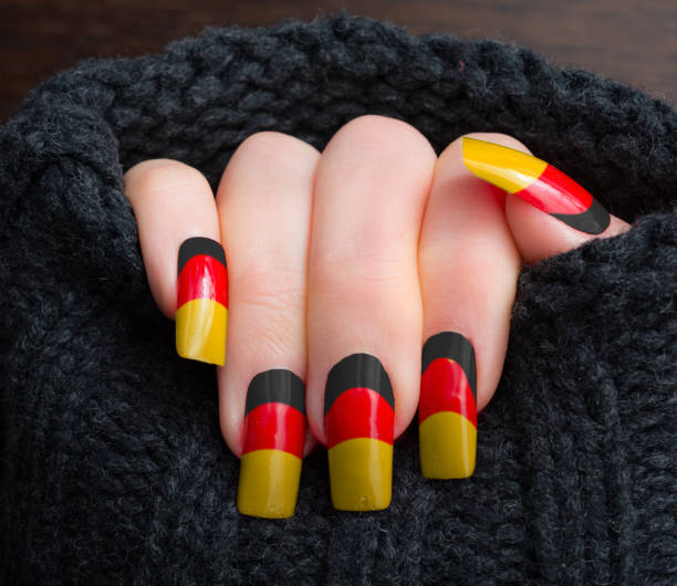 Woman showing off her german flag nails in black, red and yellow Mature woman showing off her german flag manicure in black, red and yellow yellow nail polish stock pictures, royalty-free photos & images