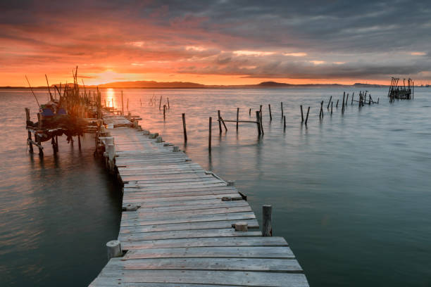 Sunset landscape of artisanal fishing boats in the old wooden pier. Sunset landscape of artisanal fishing boats in the old wooden pier. Carrasqueira is a tourist destination for visitors to the coast of Alentejo near Lisbon. troia stock pictures, royalty-free photos & images