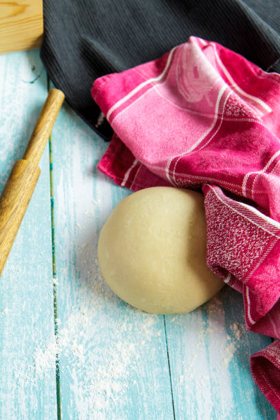 istock Dough, rolling pin and pink towel on light blue boards 951634118