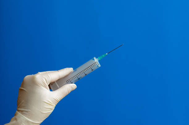 istock Syringe in hand with rubber gloves on a blue background. 951635136