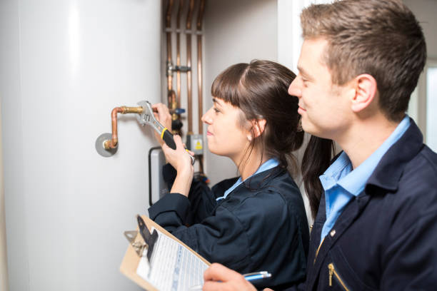 female trainee plumber working on central heating boiler with male engineer - heating engineer imagens e fotografias de stock