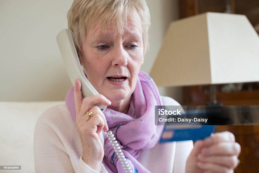 Senior Frau, die Kreditkartendaten am Telefon - Lizenzfrei Wirtschaftskriminalität Stock-Foto