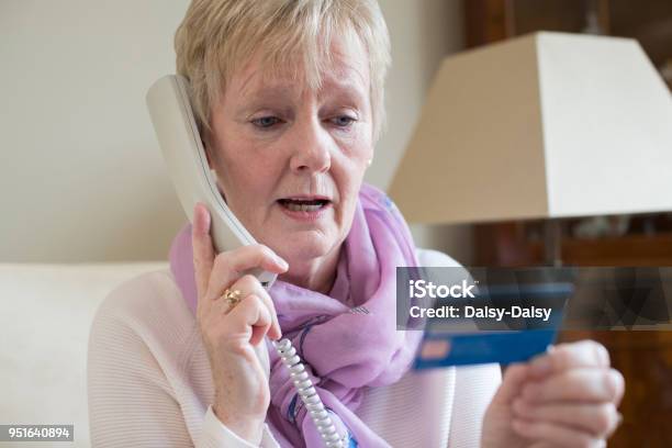 Foto de Mulher Sênior Dando Detalhes Do Cartão De Crédito Por Telefone e mais fotos de stock de Roubo Corporativo