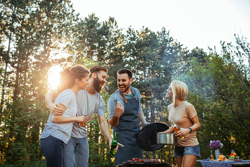 Group of happy friends making barbecue outdoors