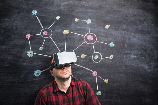 Man wearing virtual reality headset in front of abstract network drawn on blackboard