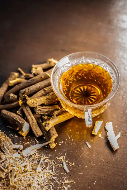 Photo of Ayurvedic herb Liquorice root,Licorice root, Mulethi or Glycyrrhiza glabra root and its powder with its tea for detoxifying the body, soothing spasms, easing menstrual cramps, raising blood pressure.