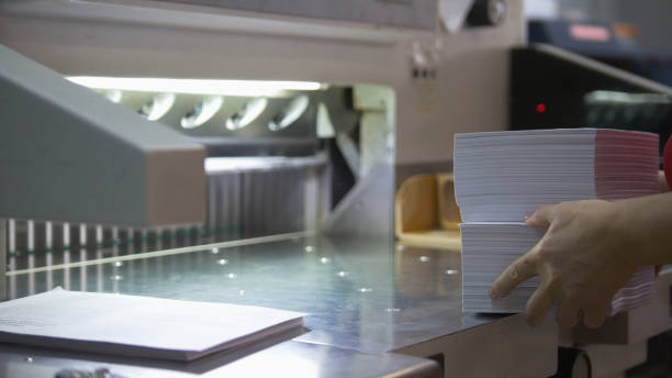 Female worker folds a stack of paper in the typography