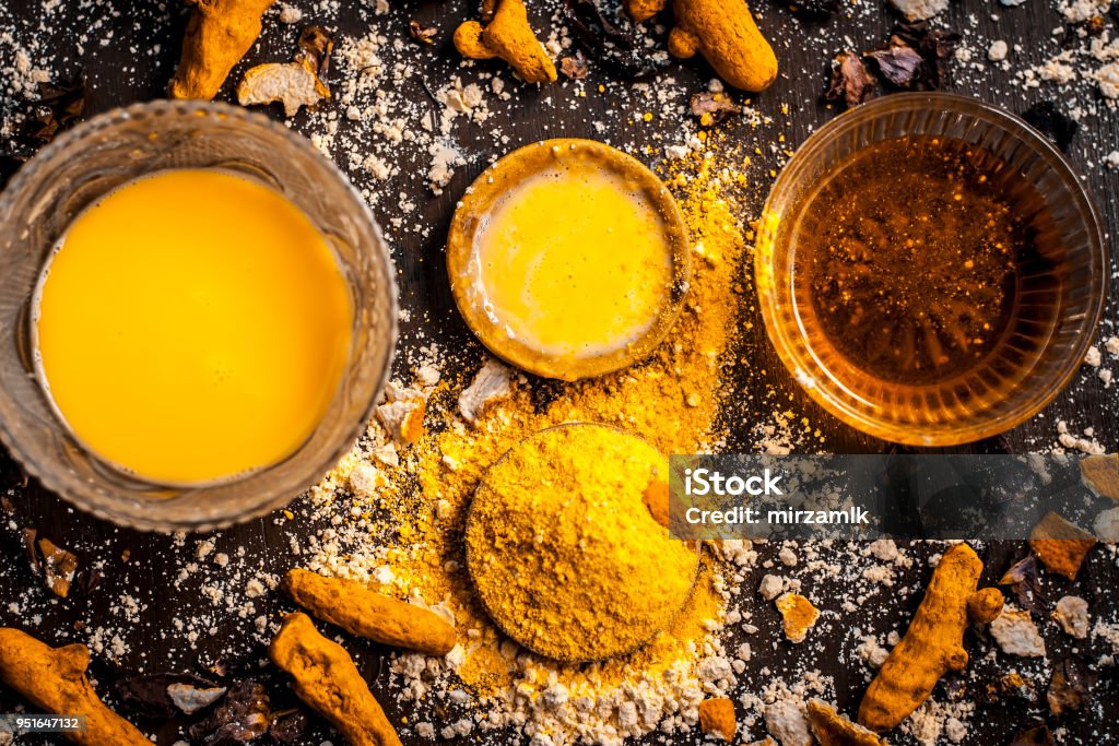 Close up of Ingredients of ayurvedic treatment or an ayurvedic face pack i.e Honey,chickpea flour and paste,turmeric powder and rose petals on a wooden surface.This face pack removes dead skin. Turmeric Stock Photo