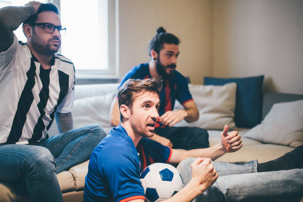 istock Male soccer fans supporting different teams watching a game together 951652512