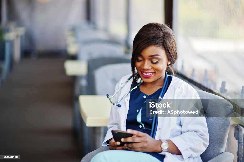 African american doctor female African american doctor female with stethoscope looked at phone and sitting on clinic. Doctor Stock Photo