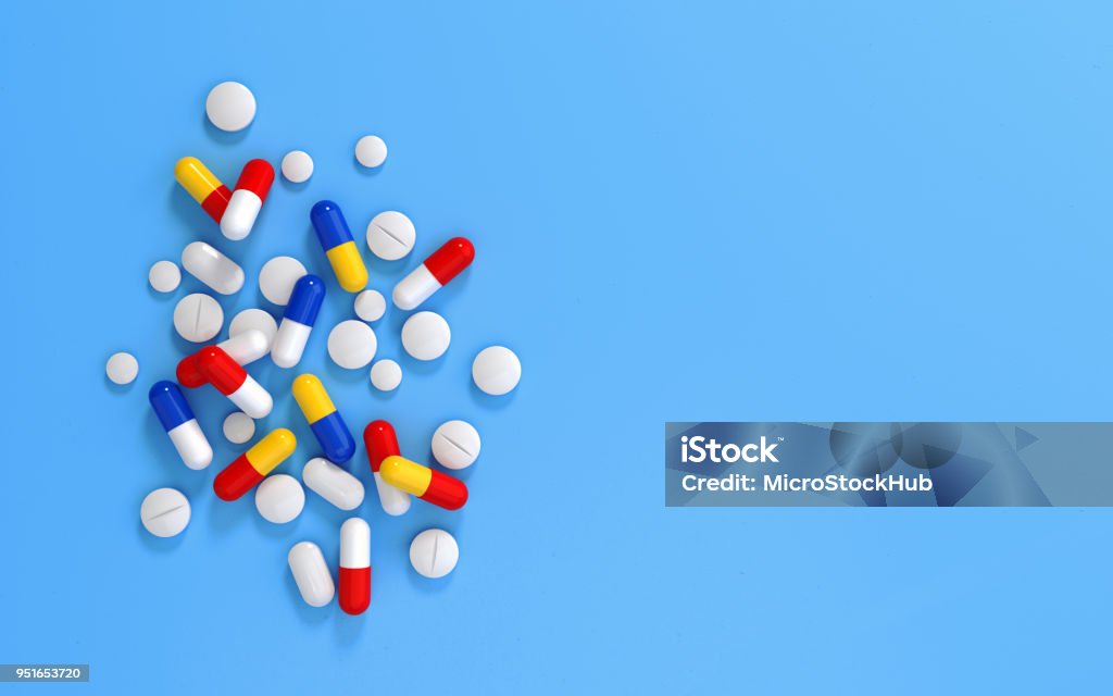 Pills On Blue Background Colorful pills scattered on blue background. Horizontal composition with selective focus and copy space. Top view. Pill Stock Photo