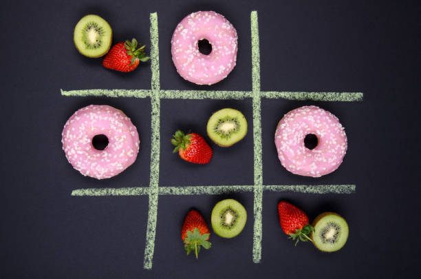 tic tac toe donuts vs. fruits tic tac toe donuts vs. fruits on black background unhealthy living stock pictures, royalty-free photos & images