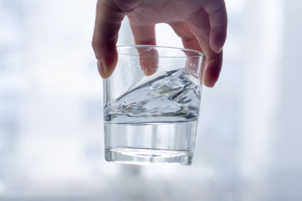 istock Hand holding a glass of water on a light background 951655076