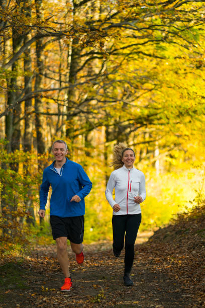 istock smiling couple jogging together in forest 951655312