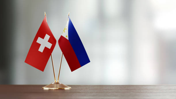 istock Swiss And Philippines Flag Pair On A Desk Over Defocused Background 951656122