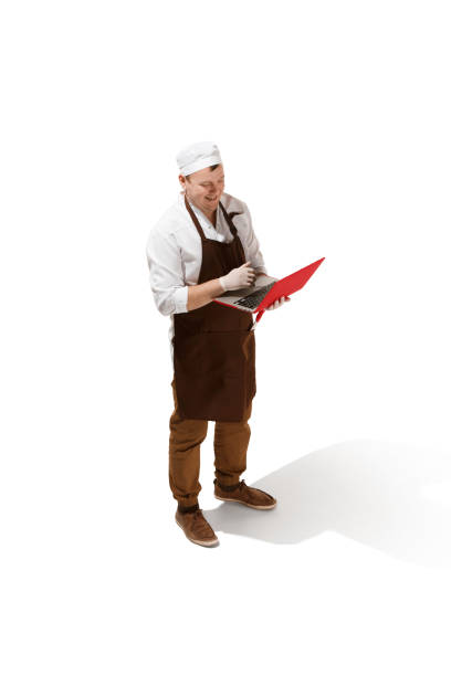 istock Serious butcher posing with a laptop isolated on white background 951656920