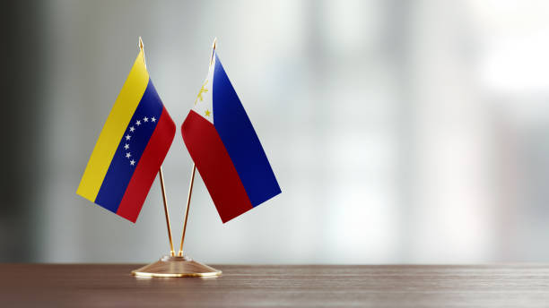 istock Venezuelan And Philippines Flag Pair On A Desk Over Defocused Background 951657592