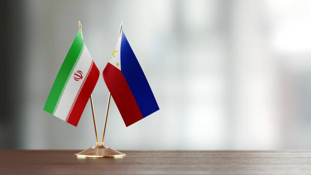 istock Iranian And Philippines Flag Pair On A Desk Over Defocused Background 951658096
