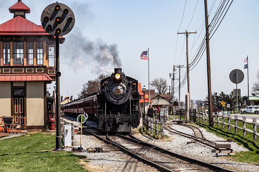 Strasburg, PA, USA - April 14, 2018:  A smokey steam locomotive operated by the Strasburg Rail Road pulls into the train station in Lancaster County, PA.