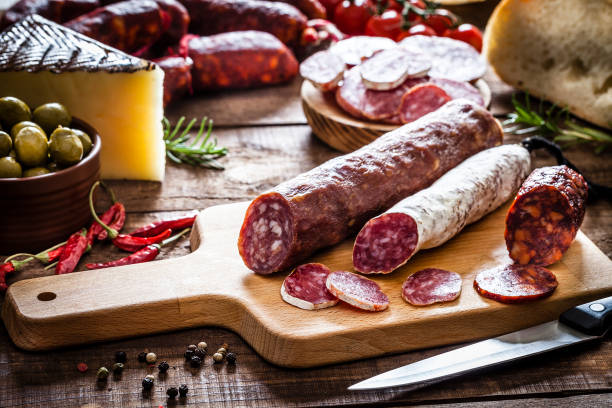 смешанные испанские части чоризо на деревенском деревянном столе - chorizo стоковые фото и изображения