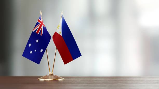 istock Australian And Philippines Flag Pair On A Desk Over Defocused Background 951659012