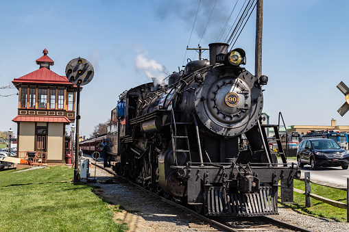 Strasburg, PA, USA - April 14, 2018:  A smokey steam locomotive operated by the Strasburg Rail Road stops at the train station in Lancaster County, PA.