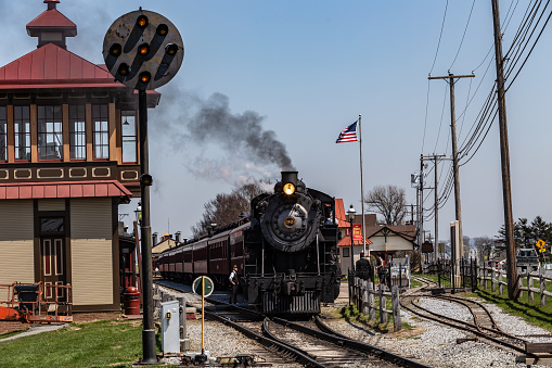 Strasburg, PA, USA - April 14, 2018:  A smokey steam locomotive operated by the Strasburg Rail Road stops at the train station in Lancaster County, PA.